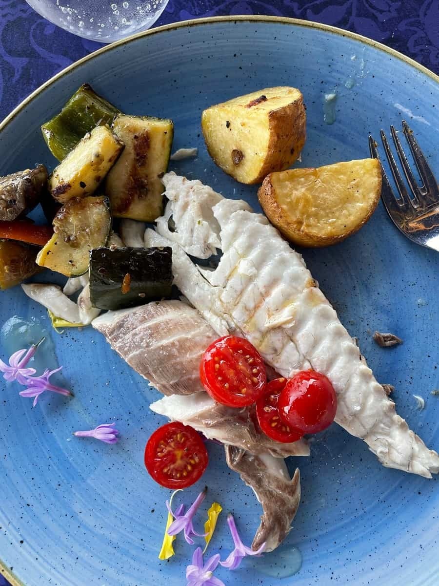 Grilled fish with vegetables on a blue plate
